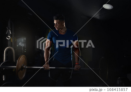 a man lifts weights in the gym and looks to the side in a tight t-shirt, creative photo a man lifts weights in the gym and looks to the side in a tight t-shirt, creative photo 108415857