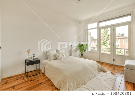 a bedroom with wood floors and white walls, including a bed in the center of the room there is a small table on the 108420801