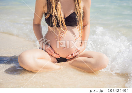 Radiant and expecting, a pregnant woman stands on a pristine snow-white tropical beach, celebrating the miracle of life against a backdrop of natural beauty 108424494
