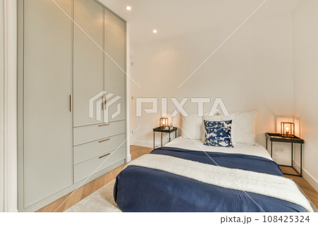 a bedroom with white walls and wood flooring the room has a bed, two nightstands and a night stand 108425324