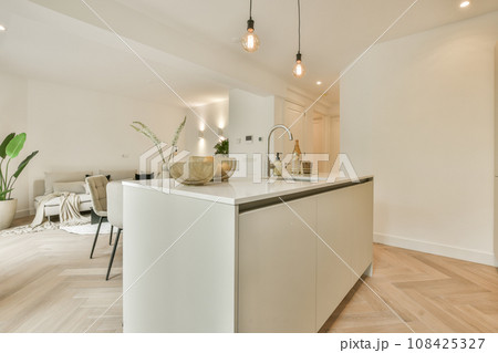 a kitchen and dining area in a house with white walls, wood flooring and light fixtures on the ceiling 108425327