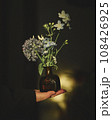 花瓶に生けられた花が西陽に照らされている 108426925