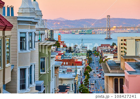 Pink sunrise lighting over residential area of San Francisco with Oakland Bay Bridge and view of bay 108427241