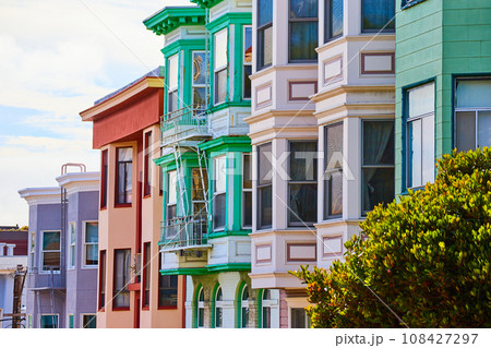 Pastel colored apartment buildings with wide array of bay windows side view Pastel colored apartment buildings with wide array of bay windows side view 108427297