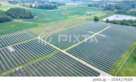 Solar panels facing straight up in aerial over solar farm with swamp and farmland around it Solar panels facing straight up in aerial over solar farm with swamp and farmland around it 108427689