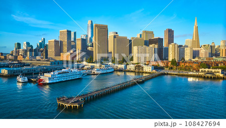 Aerial Pier 7 at sunrise with San Francisco skyscraper skyline and boats docked in bay 108427694