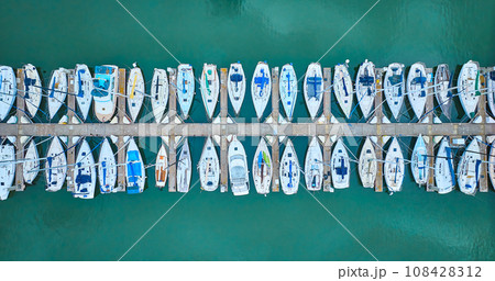 Aerial straight down view perfect row of boats on pier dock area with teal ocean water Aerial straight down view perfect row of boats on pier dock area with teal ocean water 108428312