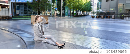 Successful businesswoman having a break, siting in city centre, looking away, adjusting her hairstyle Successful businesswoman having a break, siting in city centre, looking away, adjusting her hairstyle 108429066