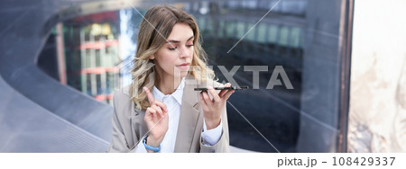 Businesswoman records voice message, dictating something on mobile phone, making a note on smartphone app Businesswoman records voice message, dictating something on mobile phone, making a note on smartphone app 108429337