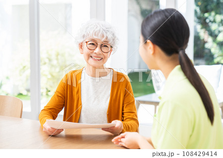 ケアマネージャーに相談するシニアの女性 108429414
