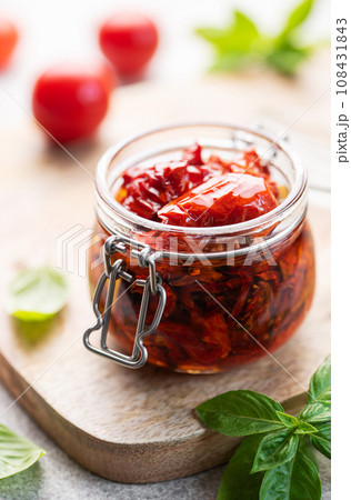 Jar with sun dried tomatoes with fresh herbs and spices. 108431843