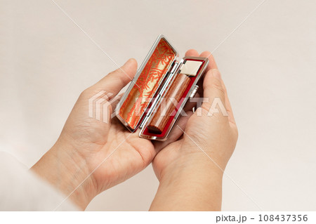 ケースに入った印鑑を大切に両手で持つ女性の手 108437356