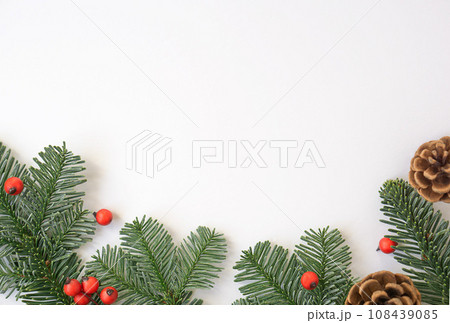 Christmas background with green branches, red berries and brown cones. 108439085