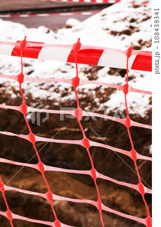 Red ribbon on construction work fence closeup 108439341