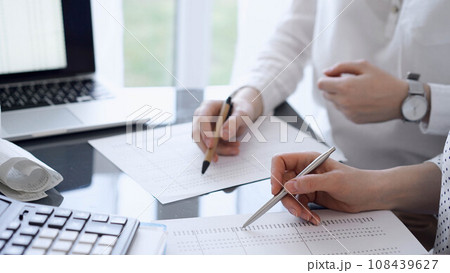 Two accountants use a calculator and tablet computer for counting taxes or revenue balance. Business, audit, and taxes concepts 108439627