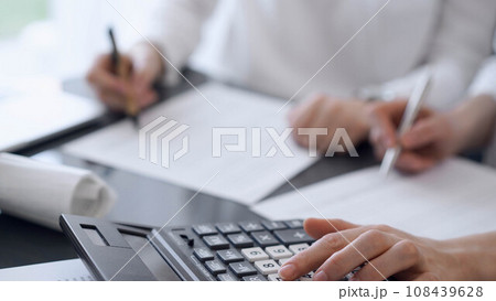 Two accountants use a calculator and laptop computer for counting taxes or revenue balance. Business, audit, and taxes concepts 108439628