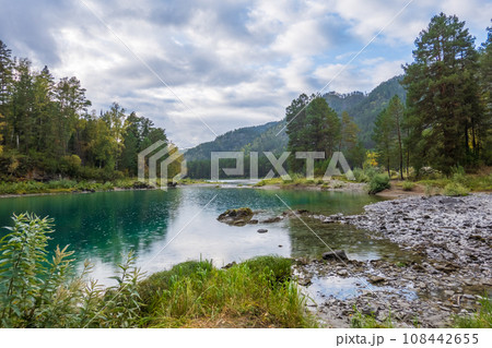 Scenic view of calm blue lake with trees and mountain against cloudy sky at Altai, Russia Scenic view of calm blue lake with trees and mountain against cloudy sky at Altai, Russia 108442655
