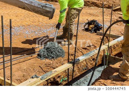 Worker pouring concrete mix foundation for new house on construction site Worker pouring concrete mix foundation for new house on construction site 108444745