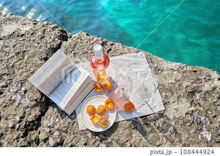 Two glasses of wine and summer fruits on the beach, sea and landscape in the background, summer picnic, travel, vacation, weekend getaway outdoors Two glasses of wine and summer fruits on the beach, sea and landscape in the background, summer picnic, travel, vacation, weekend getaway outdoors 108444924
