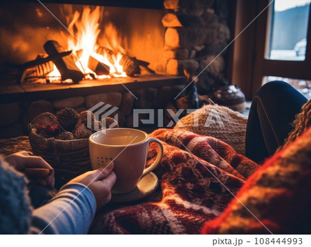 People relax sitting on the sofa and drink hot drinks near the fireplace in their home. 108444993