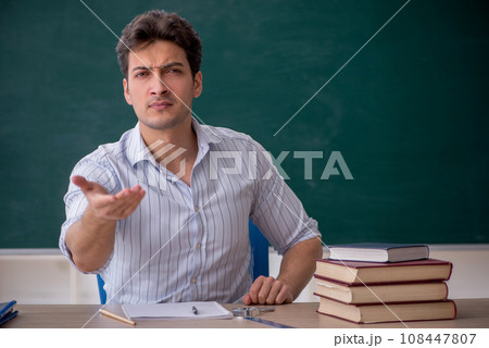 Young male teacher in front of green board Young male teacher in front of green board 108447807