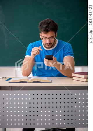 Young male student holding smartphone in the classroom 108448425