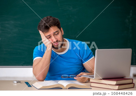 Young male teacher student in front of green board 108448426