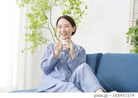 リビングでパジャマ姿で温かい飲み物を飲む女性 108451574