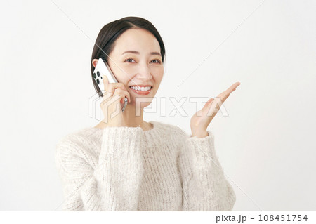 スマートフォンで通話しながら右側を手のひらで指す女性 白背景 スマートフォンで通話しながら右側を手のひらで指す女性 白背景 108451754