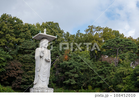 Mireuk Daebul statue of the bodhisattva Maitreya at Bongeunsa Temple, a Buddhist temple in Seoul. With background of autumn leaves. It is the tallest stone statue in Korea. 108452010