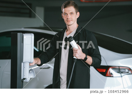 Young man travel with EV electric car to shopping center parking lot innards Young man travel with EV electric car to shopping center parking lot innards 108452966