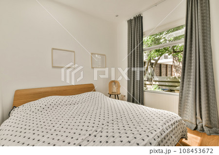 a bedroom with white walls and wood flooring, there is a bed in the room has a patterned comforter on it 108453672