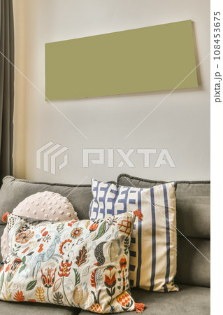 pillows on a couch in front of a wall with a green sign hanging above it that reads'free ' 108453675