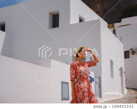 Nice asian Happy Female in boho dress Enjoying Sunny Day on Greek Islands. Travel to Lindos, Mediterranean islands outside tourist season. Tourist woman on vacation in Greece walking through the Nice asian Happy Female in boho dress Enjoying Sunny Day on Greek Islands. Travel to Lindos, Mediterranean islands outside tourist season. Tourist woman on vacation in Greece walking through the 108455332