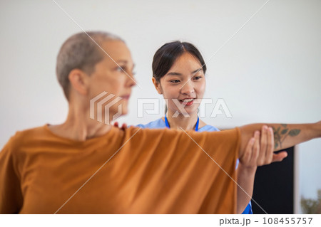 Physical therapist caregiver Asian and Caucasian senior women trust moving hand in rehabilitation. Physiotherapy healthcare, Medical caregiver consulting disabled elderly patient at home 108455757