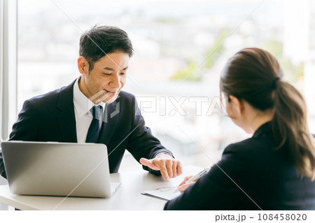 書類の説明・相談・案内するスーツ姿のビジネスマンと話を聞く女性 書類の説明・相談・案内するスーツ姿のビジネスマンと話を聞く女性 108458020