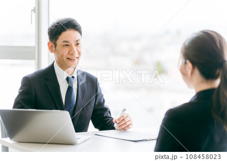 説明・相談・案内するスーツ姿のビジネスマンと話を聞くビジネスウーマン 108458023