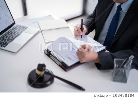 Male lawyer reading and checking financial document of business to analysis about legal agreement and terms of business contract while working on the desk with laptop technology in law firm 108458184
