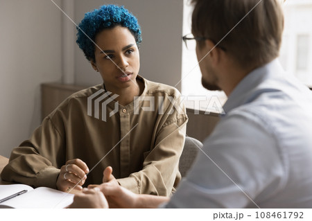 Serious young African American professional talking to male colleague 108461792