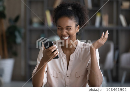 Happy young Black woman reading text on mobile phone screen 108461992