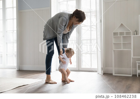 Toddler holding loving mom hands and makes first steps 108462238