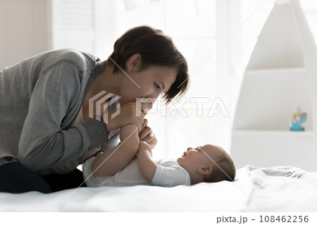 Loving affectionate mother kisses tiny toes of newborn 108462256