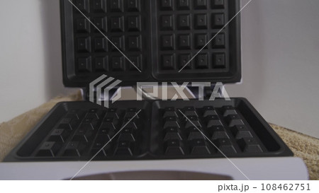 Process of making soft waffles with waffle iron. Pouring liquid dough in iron wafer placed on wooden table. Close up slow motion video clip. High quality 4k footage Process of making soft waffles with waffle iron. Pouring liquid dough in iron wafer placed on wooden table. Close up slow motion video clip. High quality 4k footage 108462751