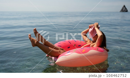 Summer vacation woman in hat floats on an inflatable donut mattress. Happy woman relaxing and enjoying family summer travel holidays travel on the sea. 108462752