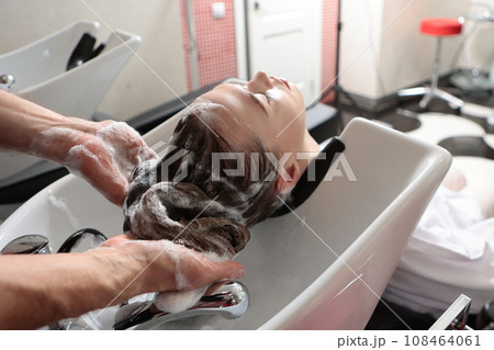 Woman undergoes hair washing procedure in beauty salon.Woman is shampooed and her hair is massaged. Concept of spa services. Woman undergoes hair washing procedure in beauty salon.Woman is shampooed and her hair is massaged. Concept of spa services. 108464061