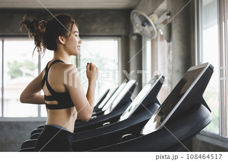 Fitness woman running on treadmill in gym Fitness woman running on treadmill in gym 108464517
