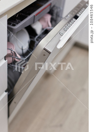 Open built-in dishwasher machine with clean cutlery, dishes, plates in white modern kitchen Open built-in dishwasher machine with clean cutlery, dishes, plates in white modern kitchen 108465546