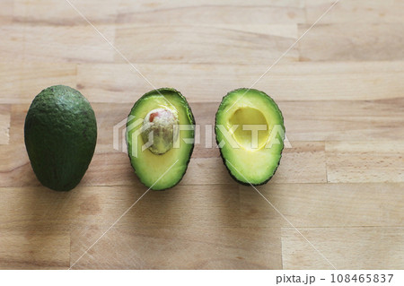 Isolated fresh organic avocados. Whole raw green avocado fruit, half with seed and a half without on wooden table. Design element for product label, catalog print, web use. Diet healthy concept Isolated fresh organic avocados. Whole raw green avocado fruit, half with seed and a half without on wooden table. Design element for product label, catalog print, web use. Diet healthy concept 108465837