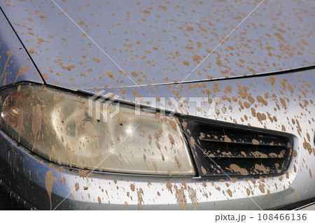 Splashes of mud. Close up of a dirty headlight of gray car with muddy splash. Car wash concepts. - Background texture. Splashes of mud. Close up of a dirty headlight of gray car with muddy splash. Car wash concepts. - Background texture. 108466136