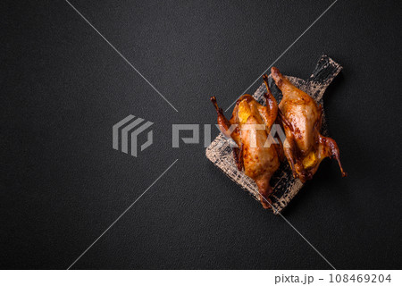 Roasted quail, partridge or pigeon stuffed with orange with spices and herbs 108469204